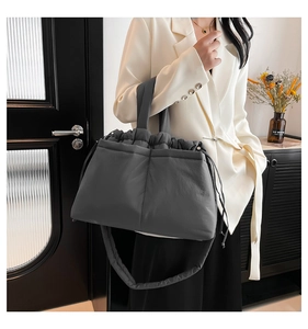Detail of dark grey quilted nylon tote bag with drawstring closure on model