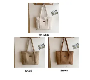 Detailed view of suede tote bag with front pocket and logo hanging on wooden hooks