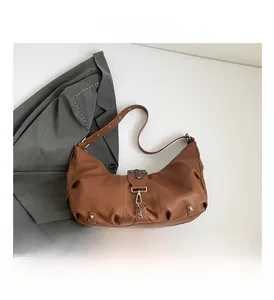 Détail du sac hobo en cuir marron avec boucle croix argentée et texture vintage