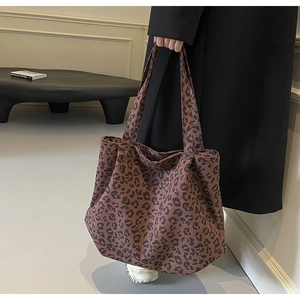 Vue détaillée du sac cabas en toile à imprimé léopard porté par un mannequin en manteau