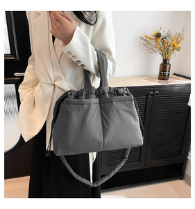 Detailed view of gray quilted puffer bag with drawstring on a white blazer model