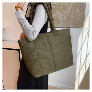 Detailed close-up of an olive green quilted nylon shoulder bag on a model for daily use