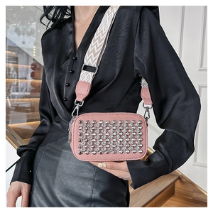 Detail of pink PU leather crossbody bag featuring rows of rhinestones and a wide strap