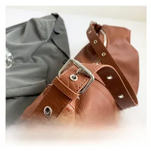 Détail de la bandoulière réglable avec œillets métalliques sur sac en cuir marron