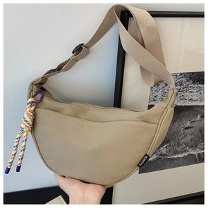 Minimalist beige half-moon shoulder bag with fabric strap and colorful rope pendant