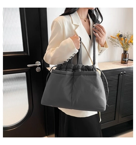 Detail of a dark gray quilted puffy tote bag featuring drawstring closure and soft texture
