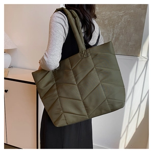 Detail of army green quilted nylon tote bag with geometric stitching on model shoulder