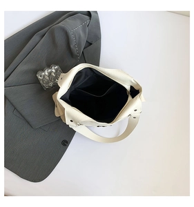 Detailansicht der weißen PU-Tasche mit Litschimuster, schwarzer Innentasche und Nieten