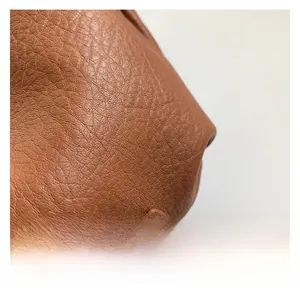 Détail de la texture cuir PU caramel avec rivets métalliques argentés et surpiqûres