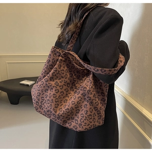Détail du sac cabas en toile à imprimé léopard porté avec une veste noire élégante