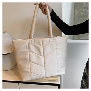 Detail view of beige quilted nylon tote bag with V-shaped stitching and long handle