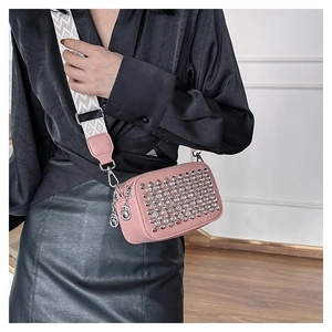 Close-up of pink PU leather crossbody bag featuring silver studs and wide woven strap