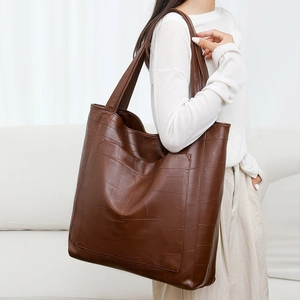 Detail of dark brown PU leather tote bag with geometric patchwork and wide shoulder strap