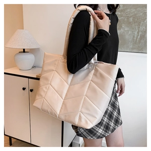 Detail of cream quilted nylon tote bag with chevron stitching and padded shoulder strap
