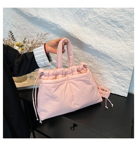 Detail of pink quilted puffer tote bag with drawstring closure and crossbody strap