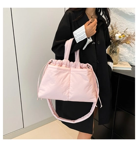 Detail of pink quilted puffer shoulder bag with drawstring closure and soft fabric texture