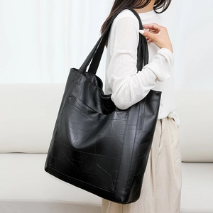 Minimalist black PU leather tote bag with geometric design worn by a model in a bright room