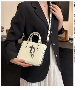 Detail of cream PU handbag with gothic metal cross charm and silver stud rivets