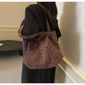 Gros plan d'un sac cabas en toile à imprimé léopard porté par un mannequin en veste