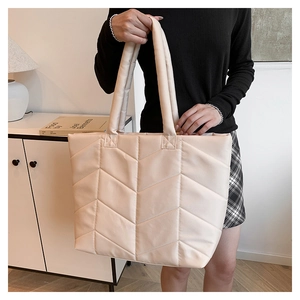 Detail of beige quilted nylon tote bag showing stitching and thick shoulder strap
