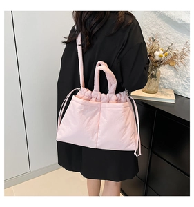 Detail of light pink quilted puffer bag showing side drawstring and soft texture