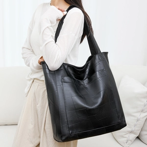 Detail shot of the black geometric patchwork PU leather tote bag on a shoulder