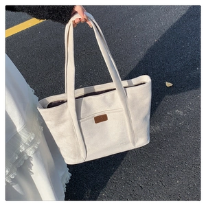 Close-up of cream corduroy tote bag with brown leather patch and zip closure detail
