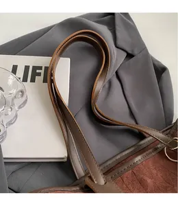 Close-up of velvet tote bag with smooth brown leather strap and neat stitching detail