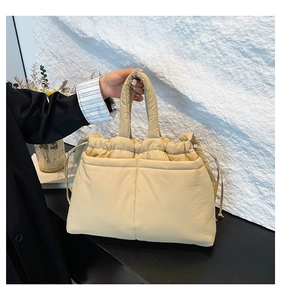 Detail of light apricot padded crossbody bag with drawstring closure and quilted texture
