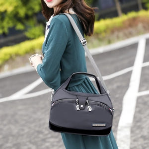 Détail du sac à bandoulière en nylon noir avec sangle grise et logo en métal mode