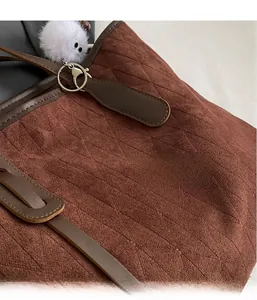 Detail of brown suede tote bag with rhombus embossing and leather strap stitching