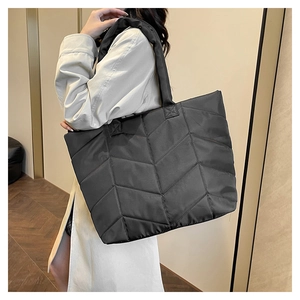 Detail shot of black quilted nylon tote bag with chevron pattern on model shoulder