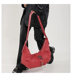 Détail du sac bandoulière rouge en similicuir avec rivets argentés et croix en métal