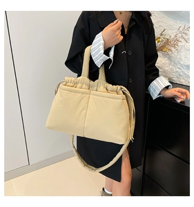 Close-up of quilted beige shoulder bag with drawstring closure worn by a model