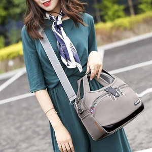 Détail du sac bandoulière gris en tissu Oxford avec large sangle et logo métal
