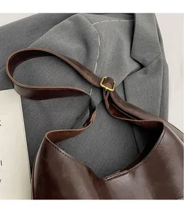 Detailed macro view of the dark brown leather shoulder strap and golden metal buckle