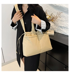 Detail view of the cream quilted puffer tote bag featuring soft drawstrings and dual front pockets