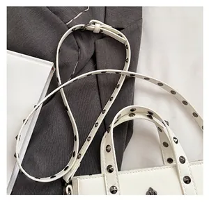 Close-up of white PU shoulder bag featuring metallic studs and cross floral hardware