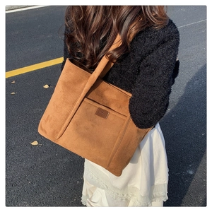 Close-up of brown suede tote bag with front pocket and leather logo for autumn style