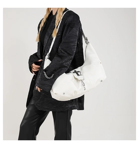 Détail du sac hobo en cuir PU blanc avec croix en métal noir et décoration de chaîne