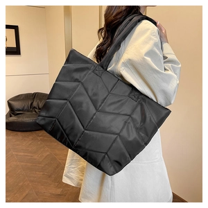 Close-up of black quilted nylon tote bag with V-shaped stitching and wide strap
