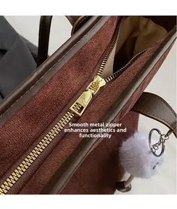 Detail view of smooth metal zipper pull and velvet texture on brown shoulder bag