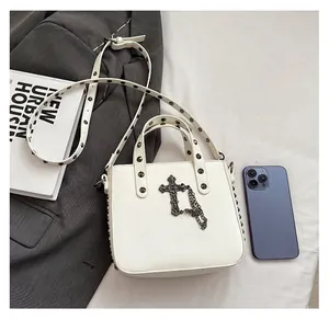 Detail view of white PU tote bag with metal rivets and Gothic cross chain decoration