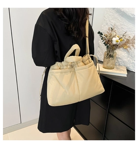 Detailed view of beige quilted bubble tote bag with soft drawstring closure on model