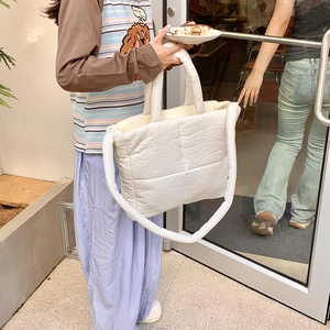 Dettaglio del tessuto trapuntato bianco della borsa tote con texture morbida e manici