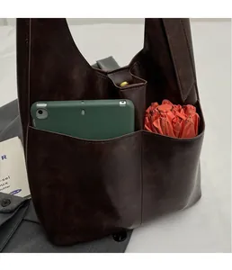 Detail view of dark brown PU tote bag with two front pockets storing a tablet and umbrella