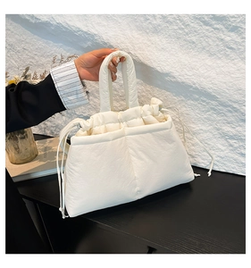 Detail of white quilted down tote bag with drawstring closure and soft padded handles