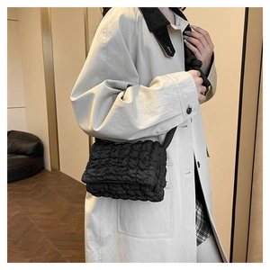 Detail der schwarzen gesteppten Nylon-Schultertasche mit flauschiger Textur am Trenchcoat