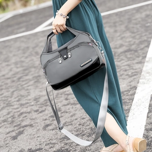 Détail du sac à bandoulière en tissu Oxford gris avec fermetures éclair et texture robuste