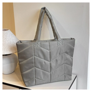 Close-up of stylish grey quilted nylon tote bag featuring a V-shaped geometric stitching design